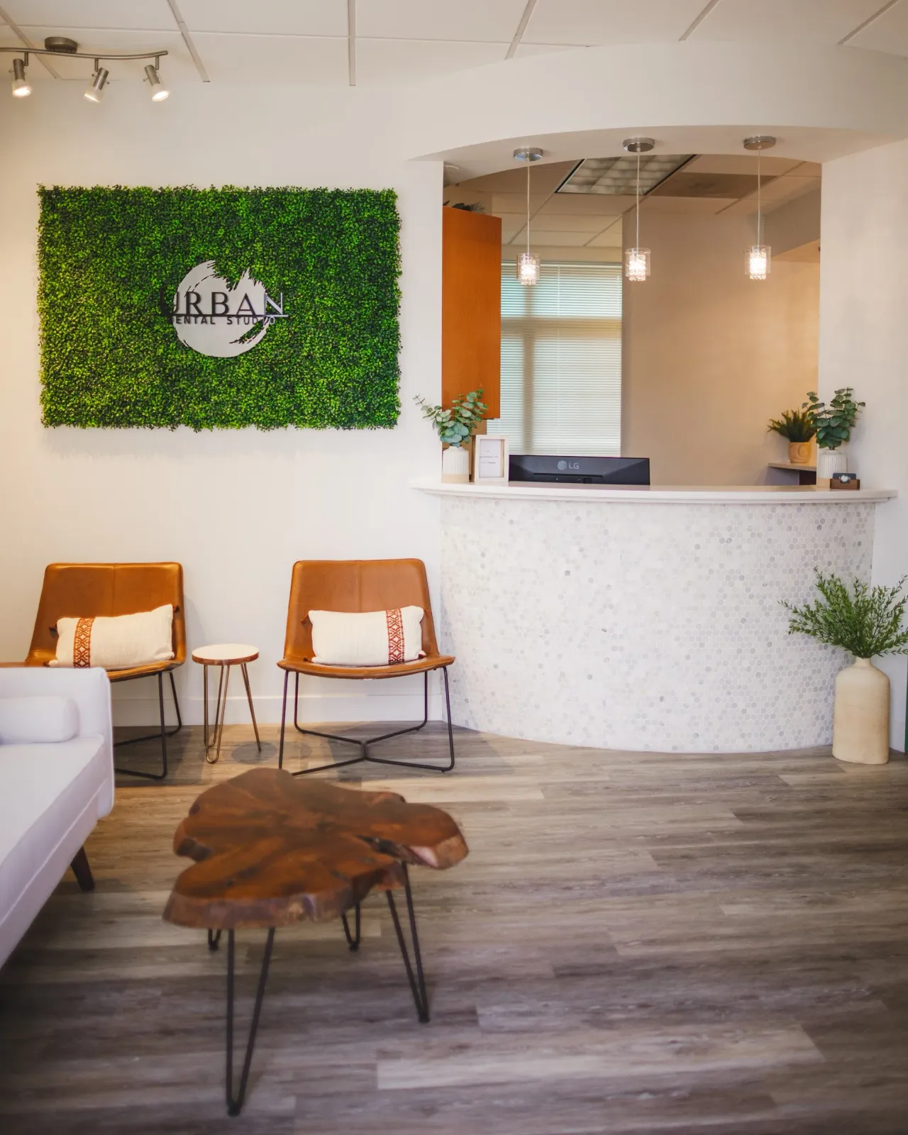 Urban Dental Studio reception with leather chairs and a curved stone desk