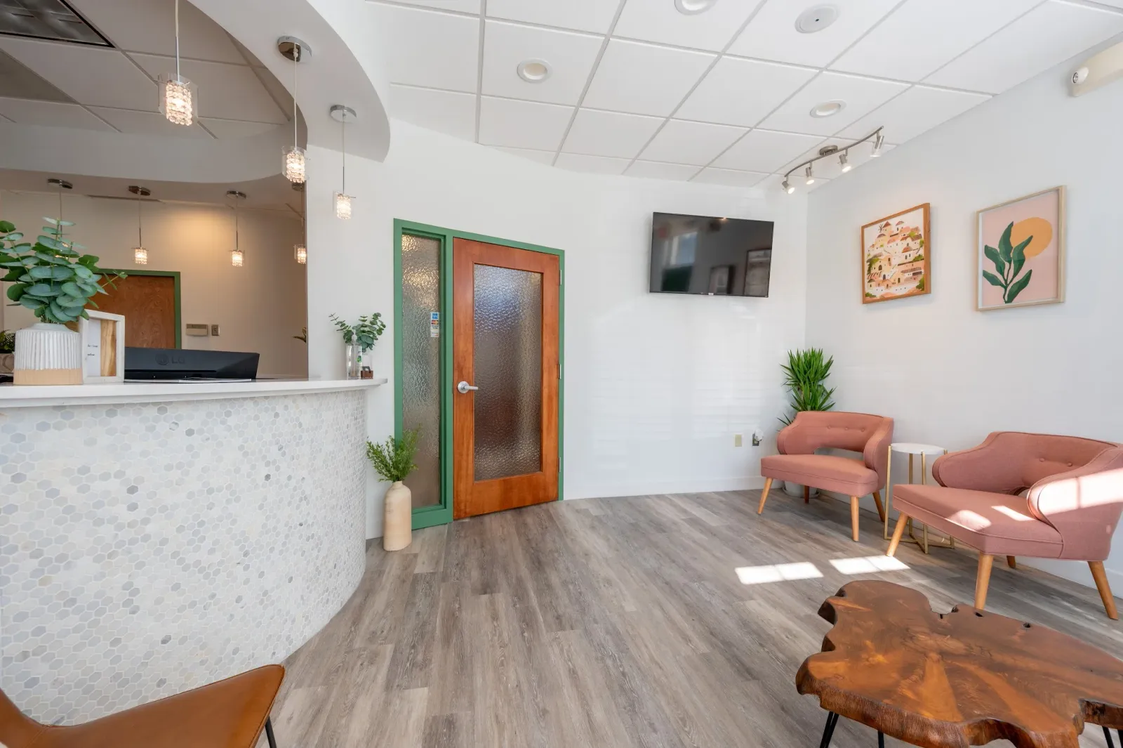 Waiting room with pink chairs, a green door, and a curved reception desk